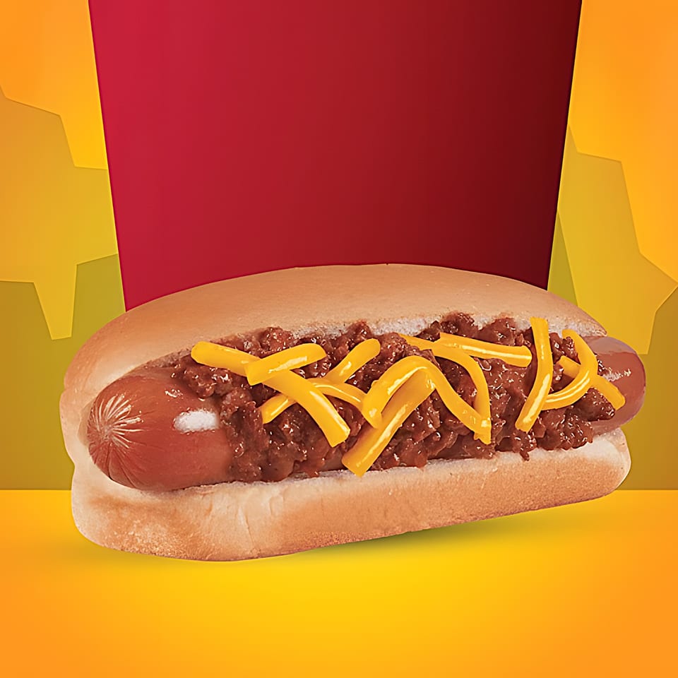 A Texas Burger Drive-In chili cheese dog with shredded cheese on a bun.