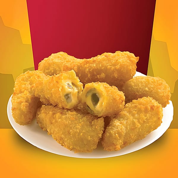 A white plate piled high with golden-brown, breaded jalapeño poppers, one broken open to show melted cheese.
