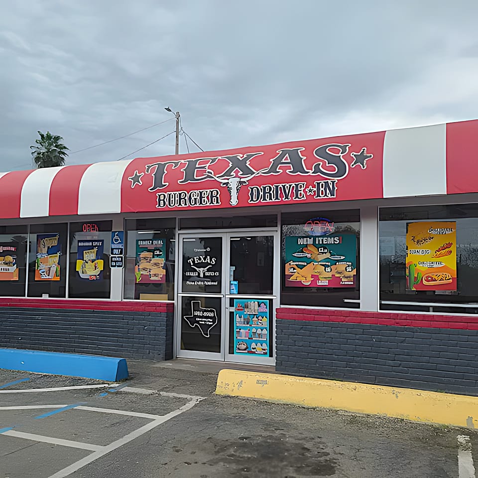Exterior of Texas Burger Drive-In with a red and white striped awning and menu posters in windows.