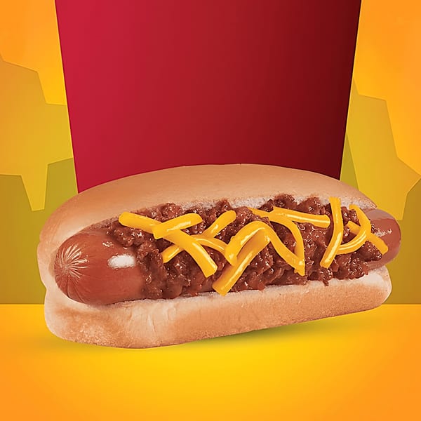 A chili cheese hot dog with shredded cheddar cheese on a bun, against a red and yellow background.